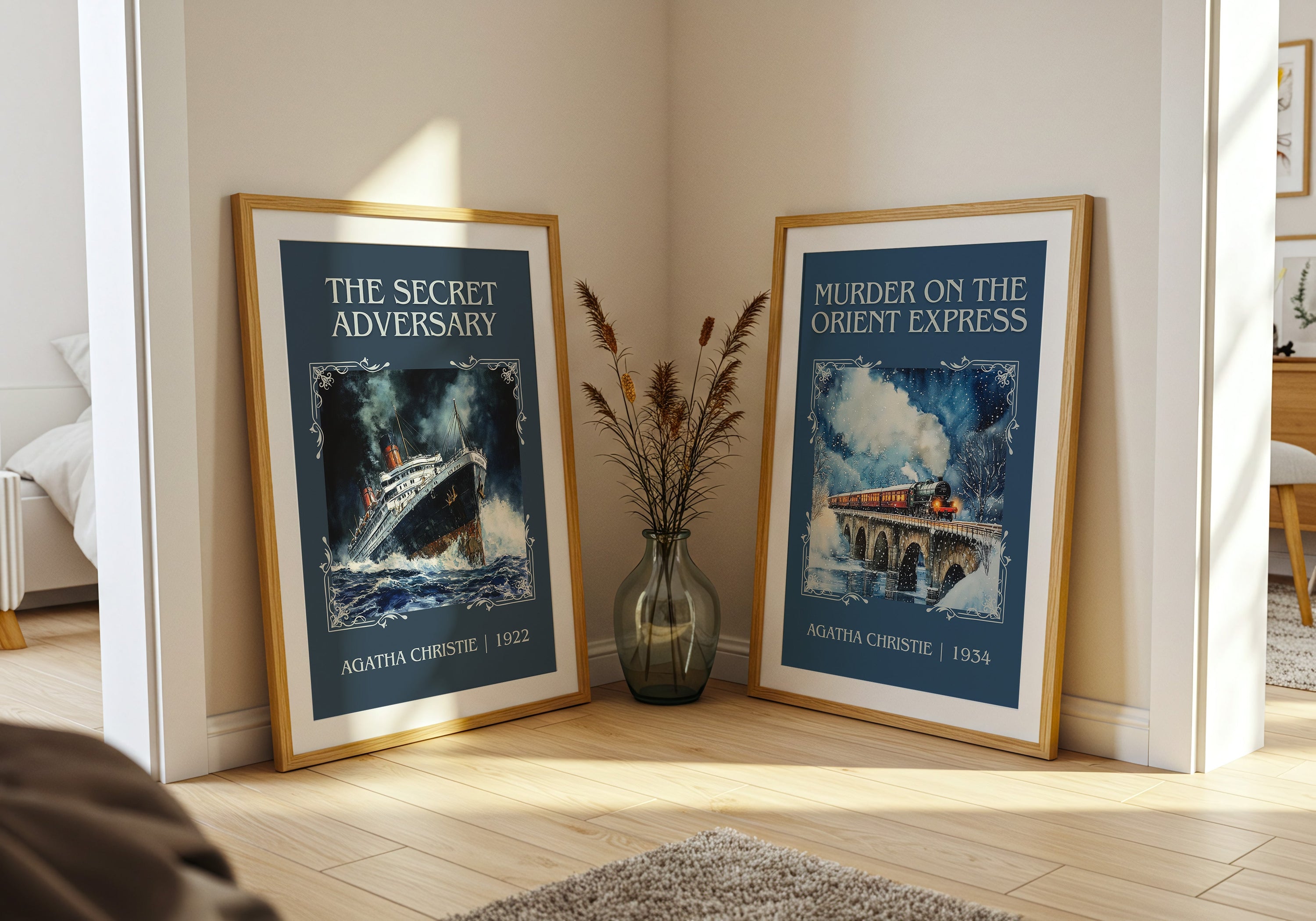 Two framed Agatha Christie book cover art prints leaning in a corner with a vase and dried plants on wooden floor