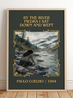 By The River Piedra I Sat Down And Wept Classic Book Art Print by Paulo Coelho – framed print leaning on a wooden floor